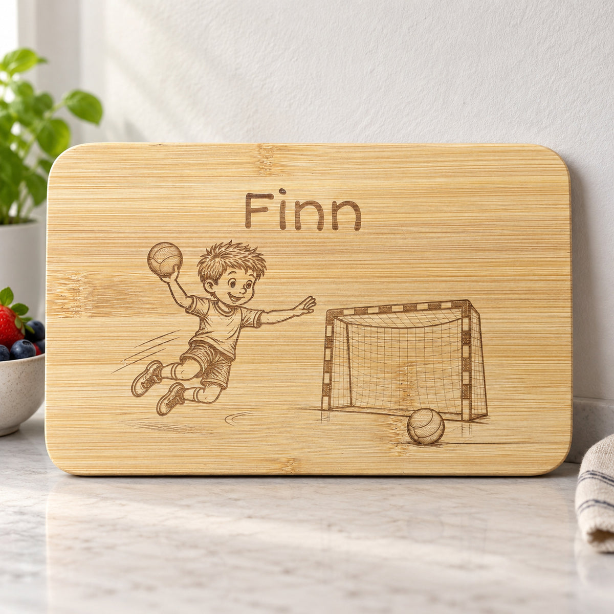Personalisiertes Frühstücksbrettchen aus Bambus mit Handball-Gravur und Wunschgravur, vertiefte dunkelbraune Lasergravur, 22 x 14 cm.