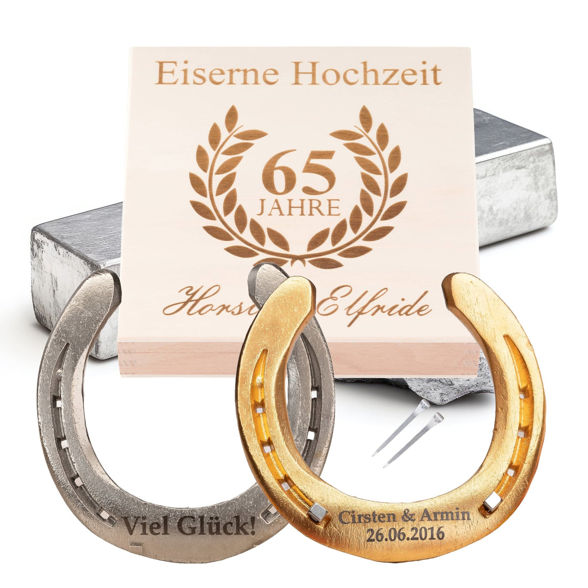 Glückshufeisen zur Eisernen Hochzeit vor der Holz-Geschenkbox, Deckel graviert mit Lorbeerkranz und Namen, dazu zwei Hufnägel