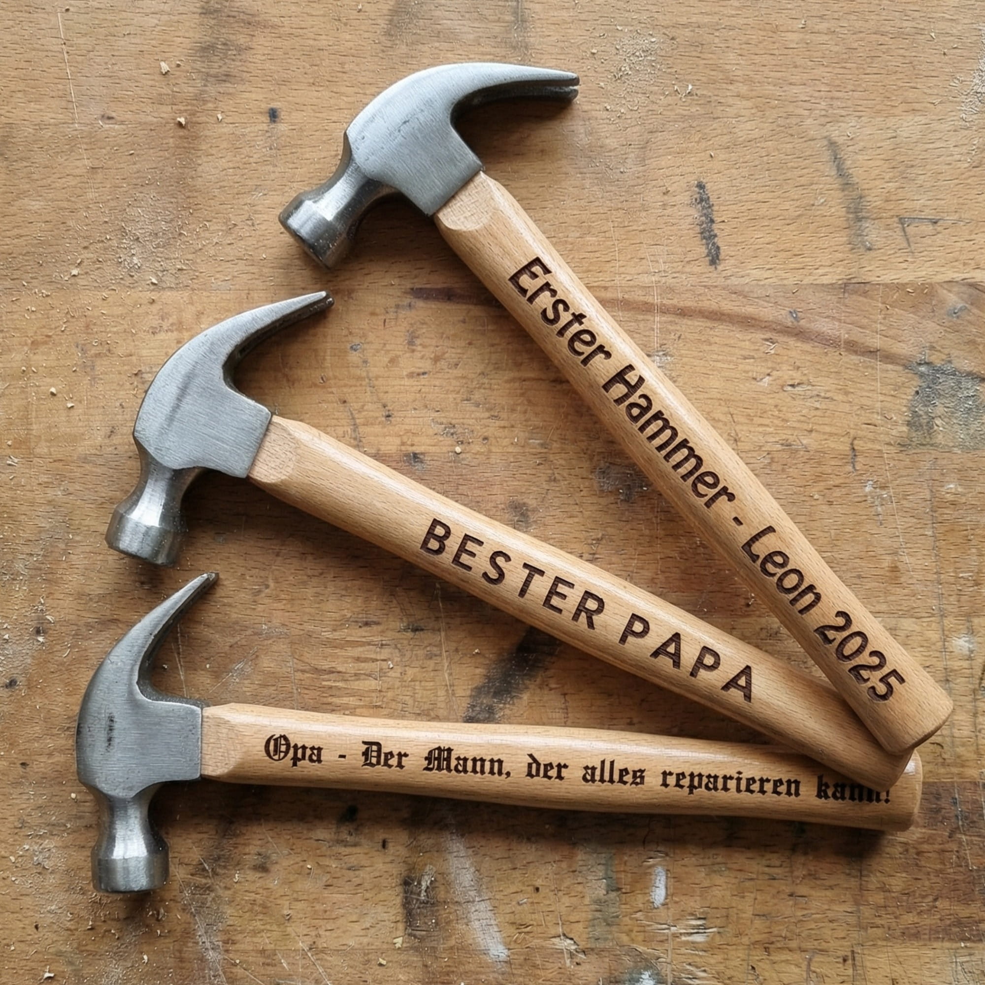 Personalisierter Hammer mit Gravur liegt auf Werkbank, drei Varianten mit unterschiedlichen Schriftarten für Papa und Opa Geschenk