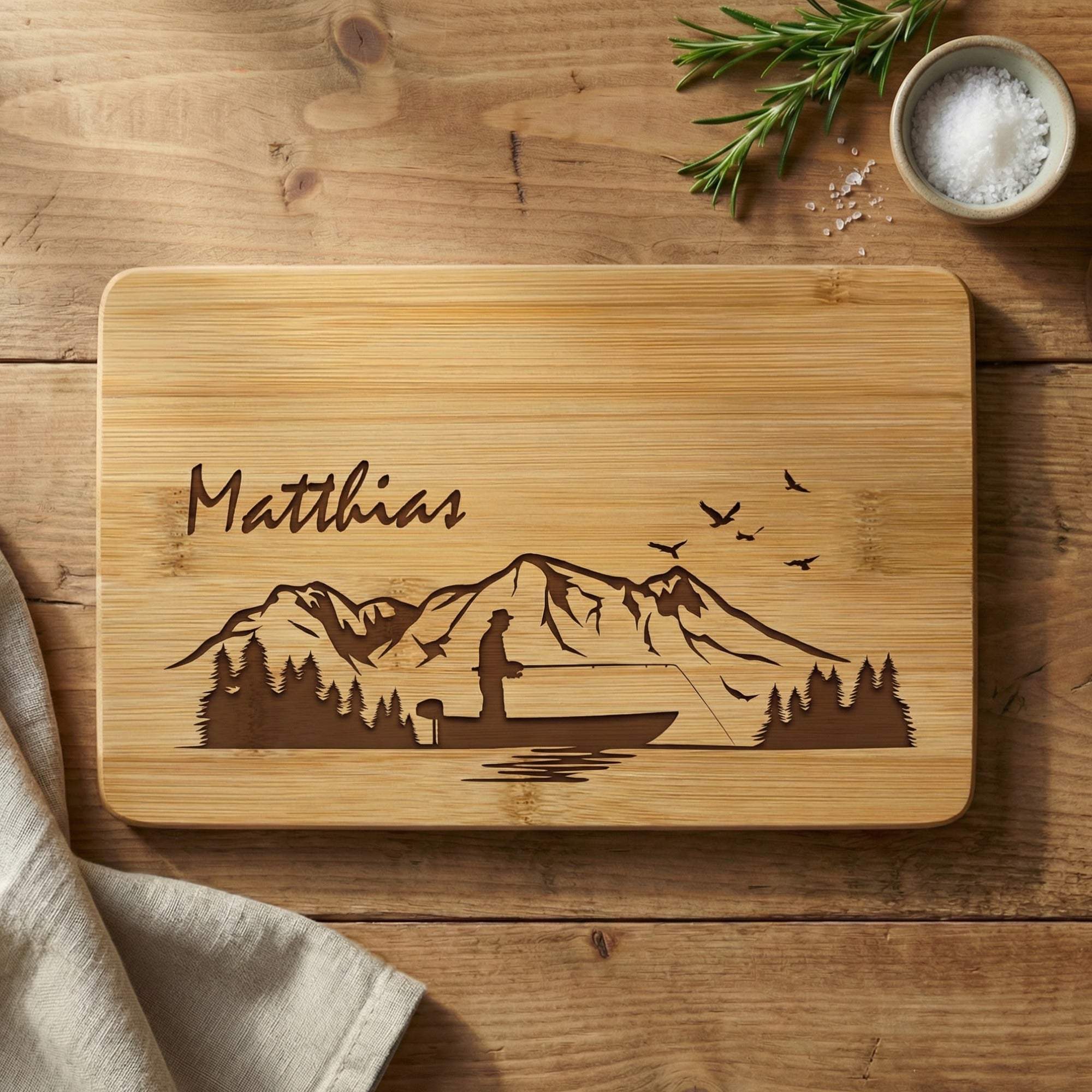 Personalisiertes Frühstücksbrettchen aus Bambus mit Lasergravur für Angler, Angelmotiv mit Boot, Bergen und Wald sowie Name Matthias