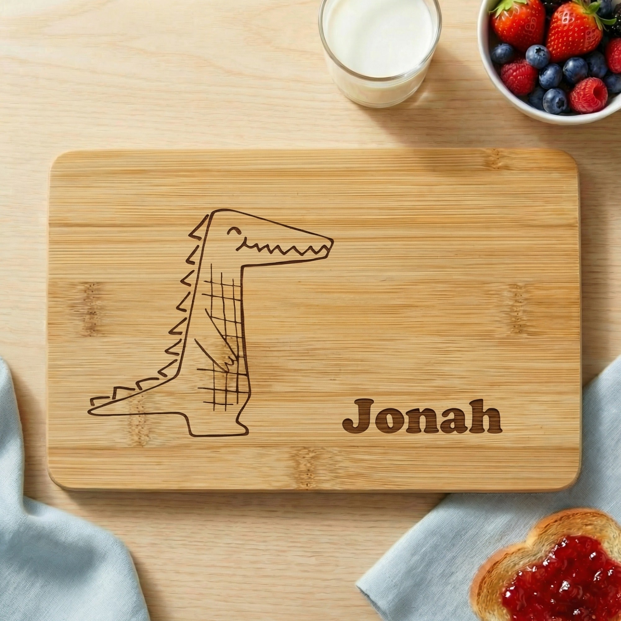 Personalisiertes Frühstücksbrettchen für Kinder aus Bambus mit Krokodil Motiv und Name Jonah, dekoriert mit Frühstück