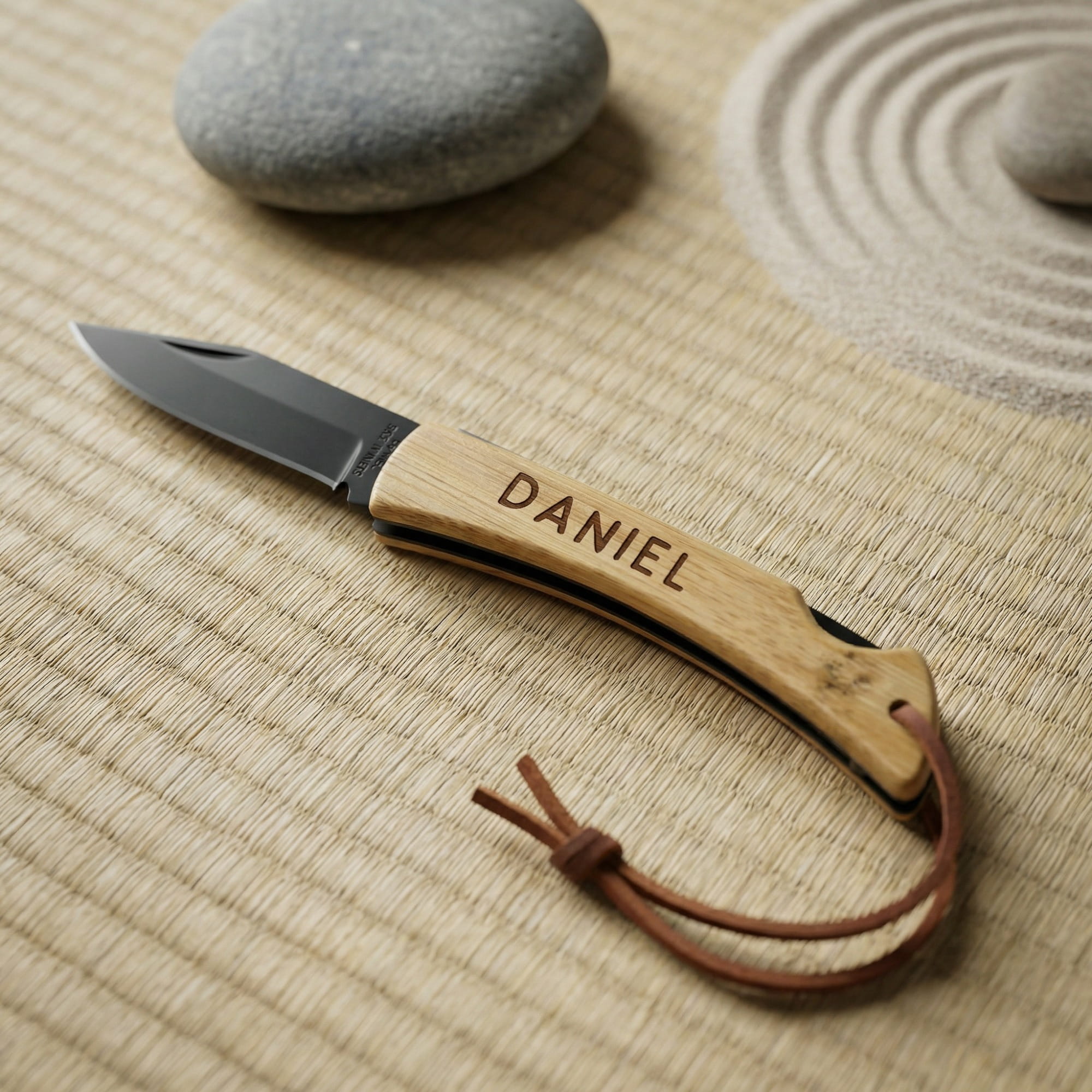 Personalisiertes Taschenmesser mit Bambusgriff und schwarzer Edelstahlklinge auf Tatami-Untergrund